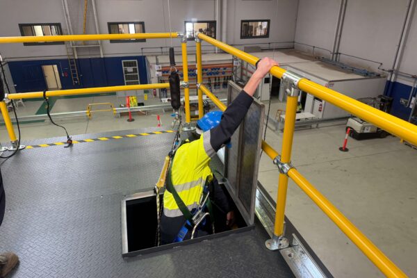 Learner in a full harness descending through a rig-deck hatch on a fall-arrest line, during confined space entry practice at Paratus Training, Bayswater WA.